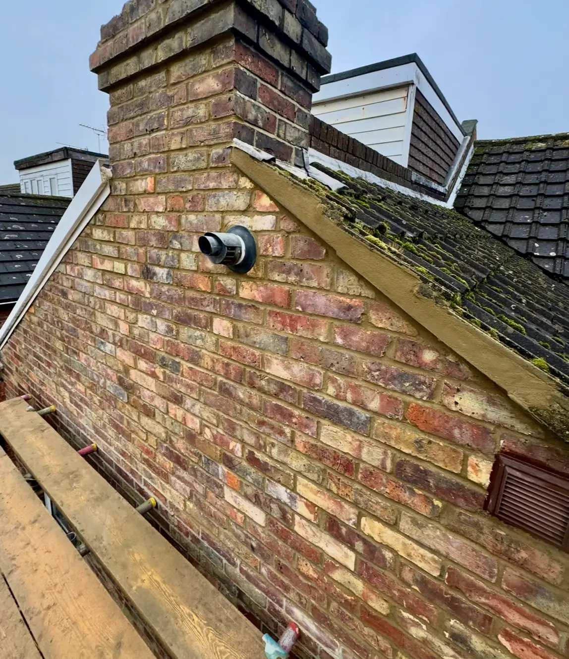 Close-up of spalling bricks on a chimney, where the faces are flaking and chipping away due to moisture damage.