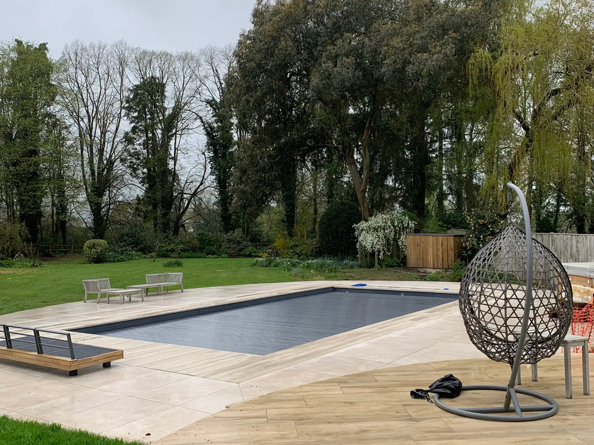 A minimalist patio featuring large-format grey porcelain slabs and a modern fire pit