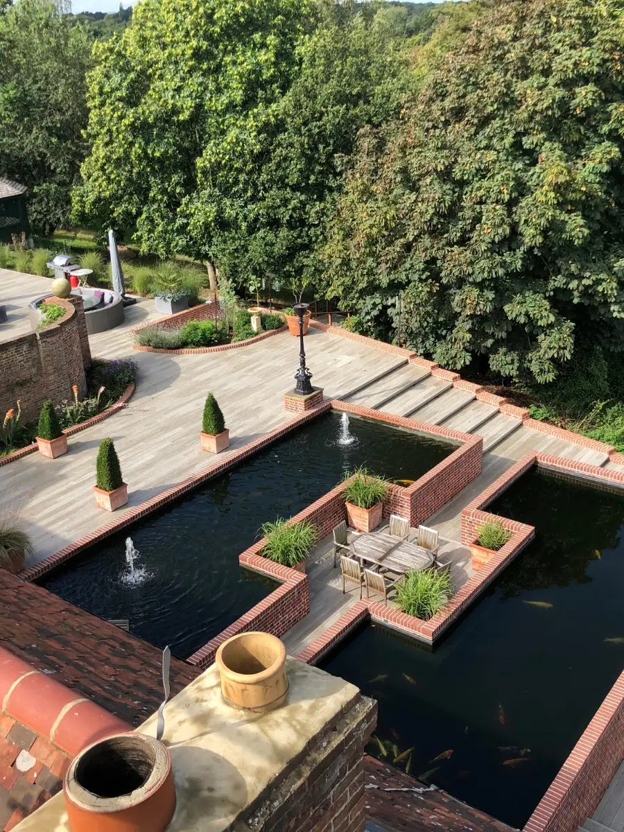 Bespoke timber pergola and relaxation zone in a Kent garden with raised herb planters and seating.