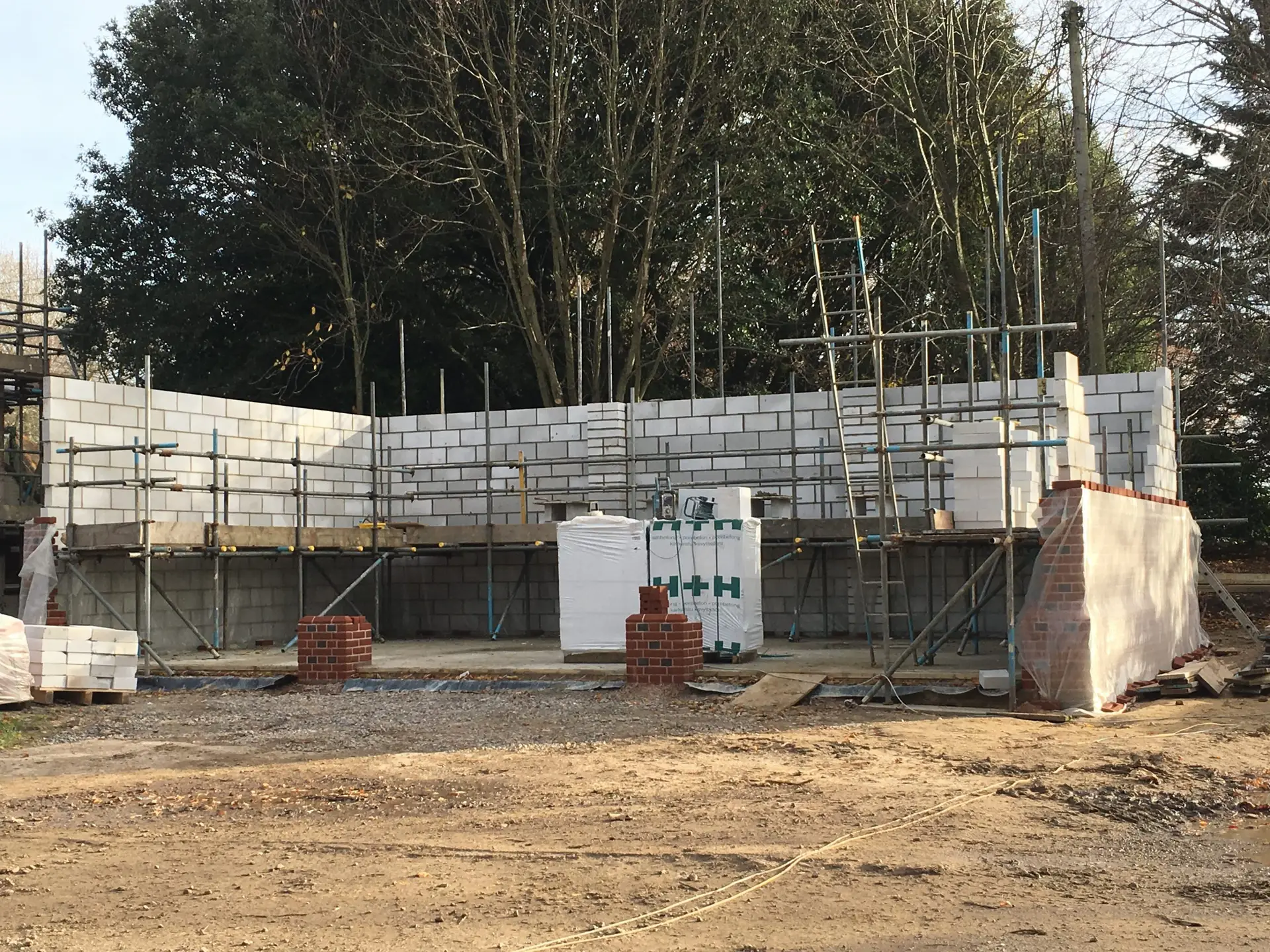 Builders Hastings using precision laser levels to prepare a flat sub-base for a durable extension.