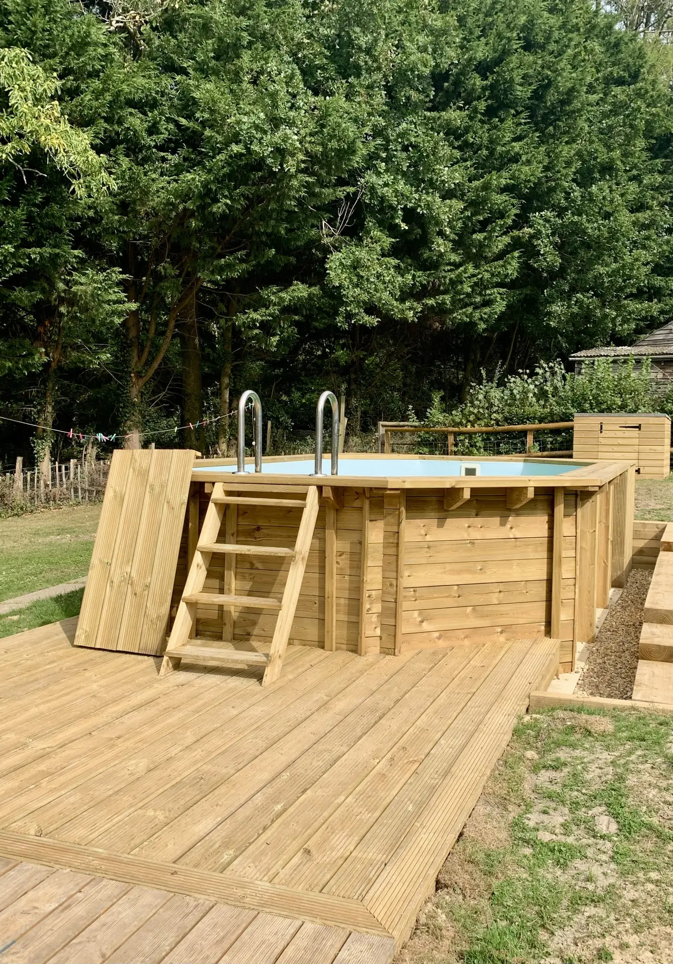 Luxury concrete swimming pool with stone surround and wooden decking by builders in Hastings.