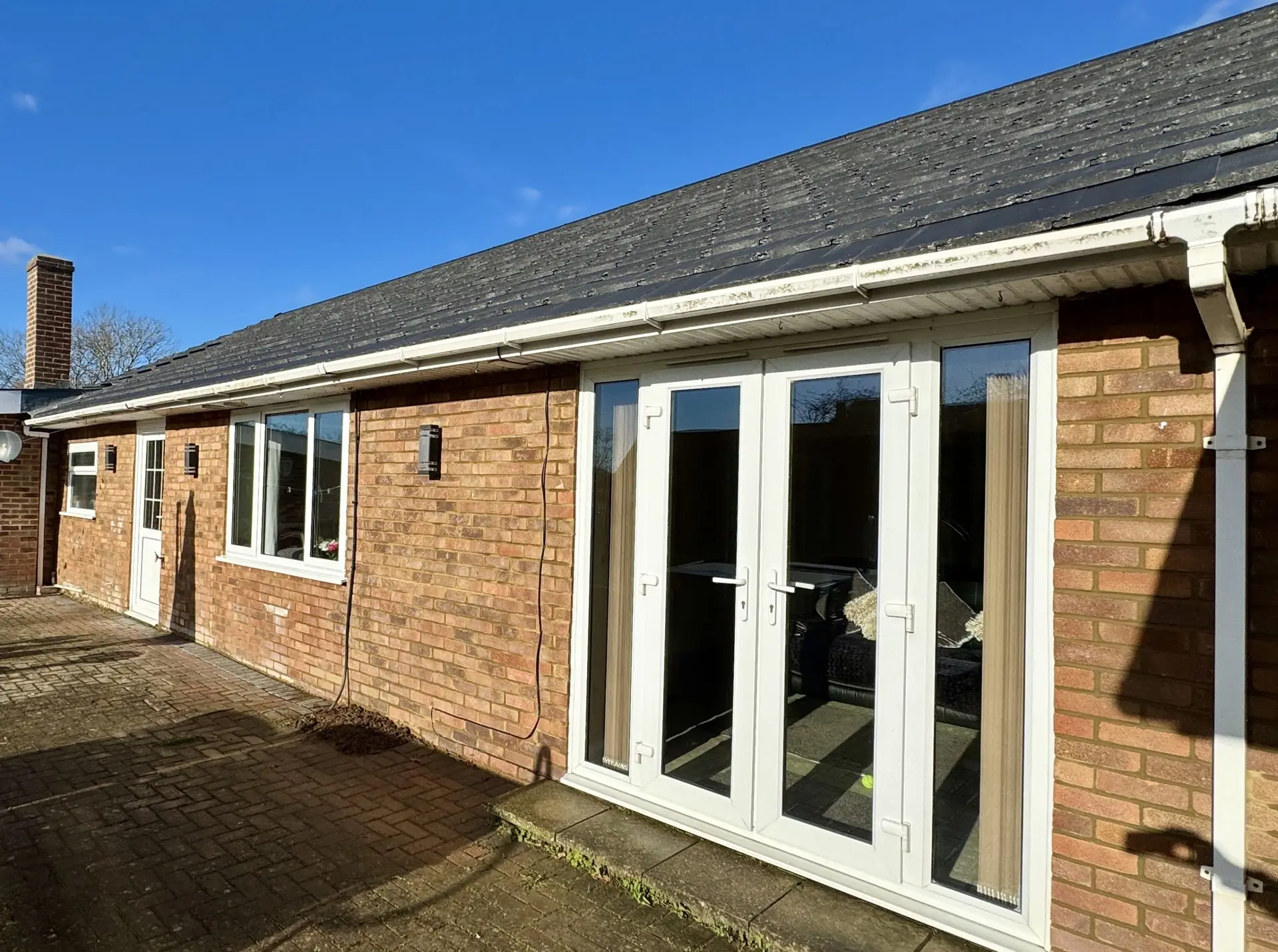 Modern living area in a Tenterden new home with exposed oak beams and large windows for natural light.